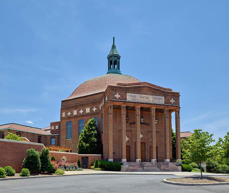 red brick baptist church surrounded by trees 