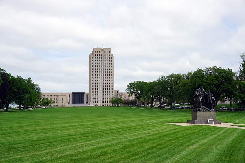 bismarck green field with a monument and a white tall building
