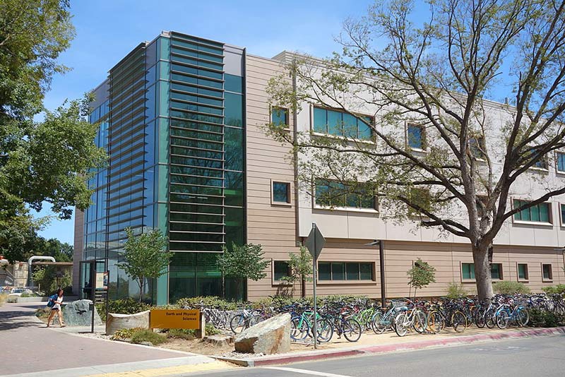 a photo of university of california's earth and science building with bicycles parking in front of it