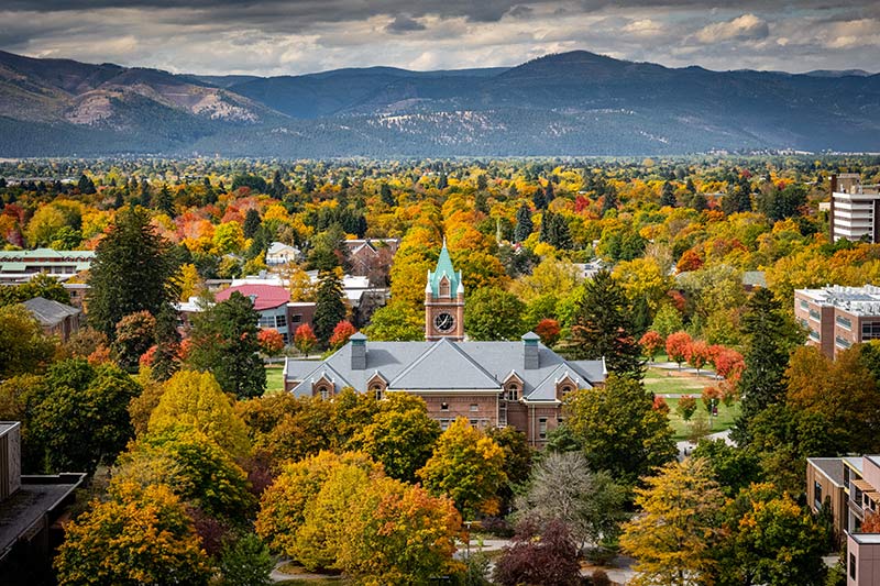 a beautiful view of um bell tower and surrounding nature and mountains