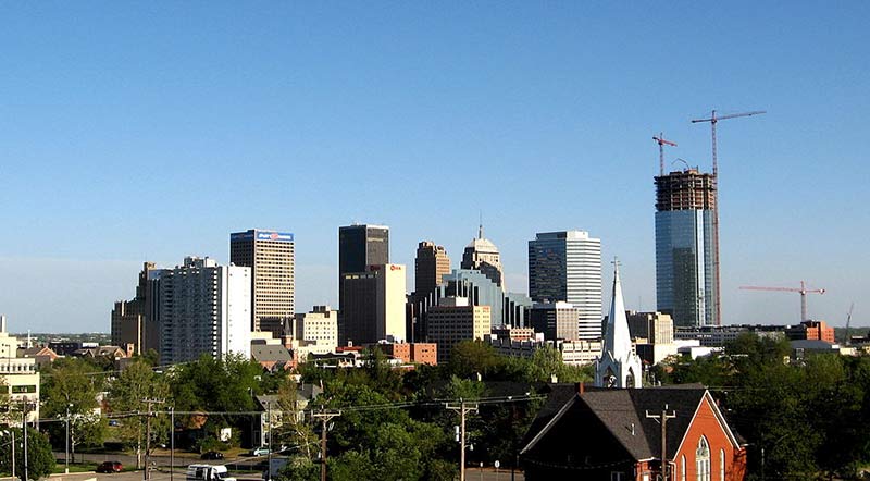 a view of downtown oklahoma with lots of skyscrapers, a church and some construction sites in distance