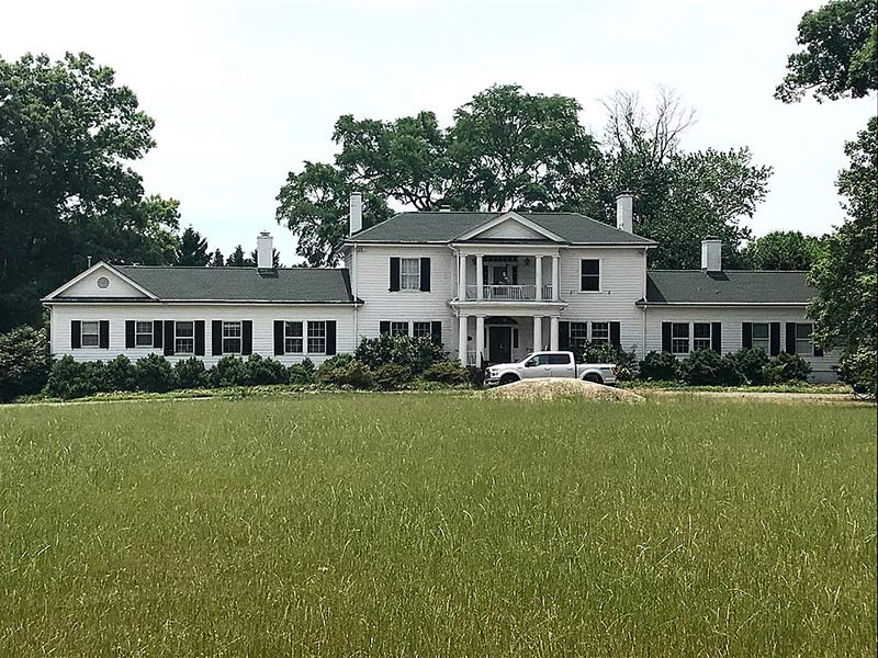 a white house complex with a gray roof
in the middle of a field